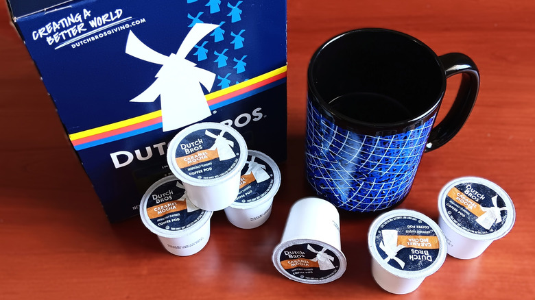 Dutch Bros caramel mocha coffee pods on table with black and blue mug of coffee.