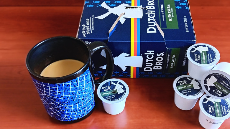 Dutch Bros Irish cream coffee pods in its box and on loose on the table with mug of coffee.