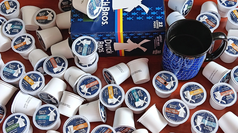 Dutch Bros box of coffee pods surrounded by loose pods and a mug of coffee.