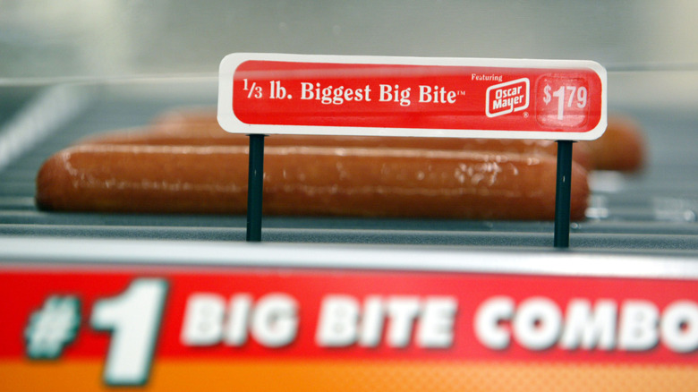A Biggest Big Bite hot dog from 7-Eleven sitting on a roller with a price tag that says $1.79