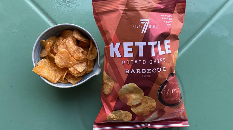 Crispy orange potato chips in blue bowl and red plastic bag