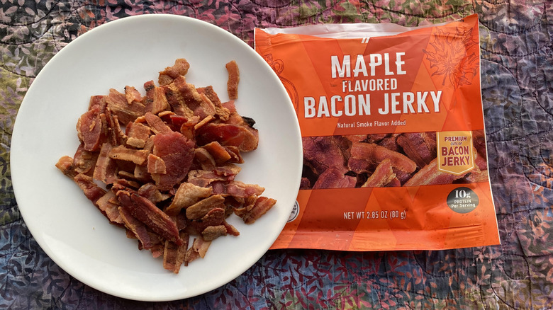 Piled jerky on white plate near orange maple bacon jerky package