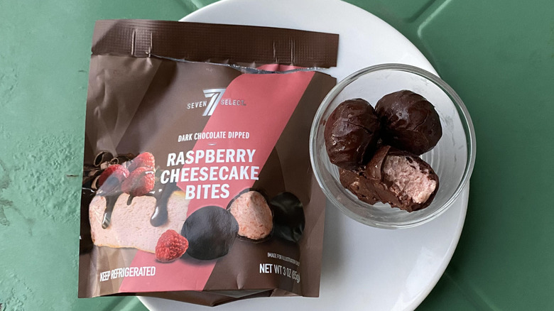Chocolate-coated cheesecake bites with pink filling next to brown and pink bag