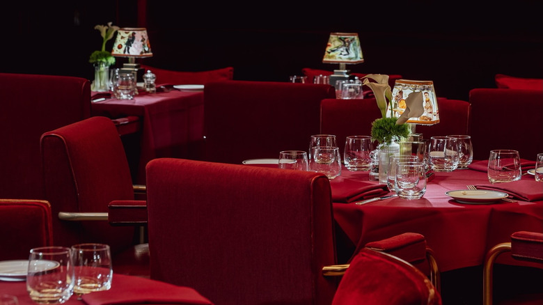 plush red chairs surrounding round, red tables with plates and cups on them