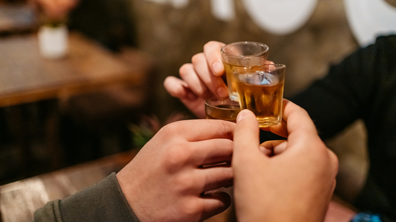 Close-up of people's hands, cheering with alcohol shots