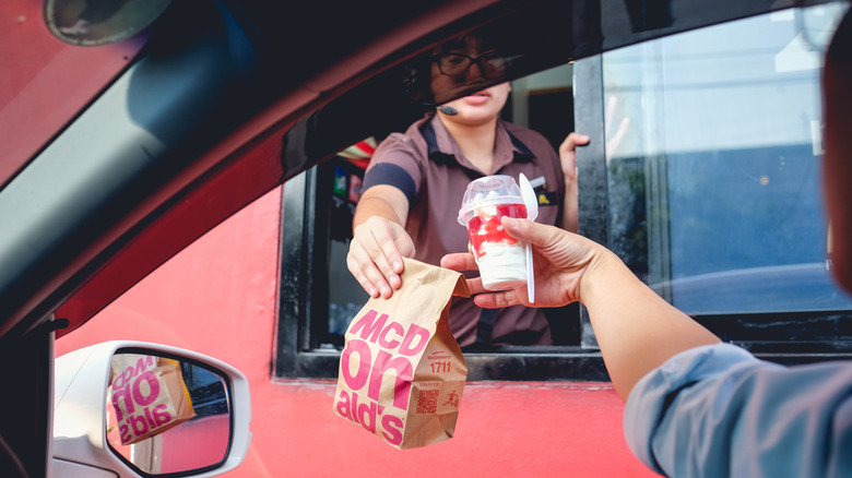 Fast food employee handing food to customer in car