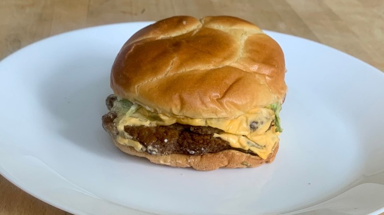 Checkers and Rally's double cheeseburger on white plate with wooden background