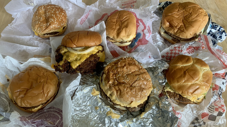 seven fast food double cheeseburgers on top of wrappers on wooden table