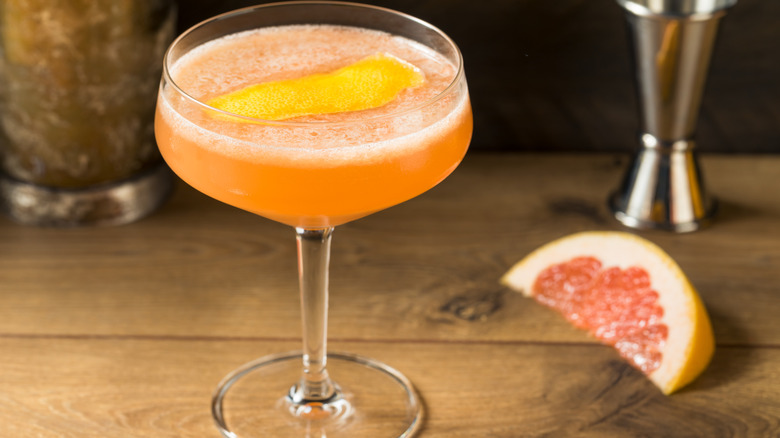 A pink cocktail next to a grapefruit