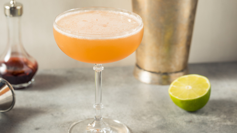 An orange cocktail next to a lime