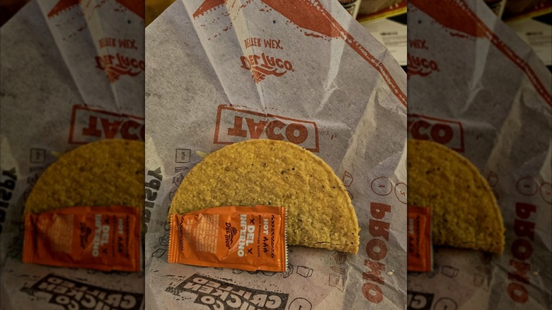 Mirrored image of Del Taco taco on packaging next to sauce packet