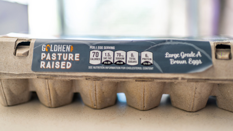 A dozen Aldi chicken eggs in cardboard container on a white surface