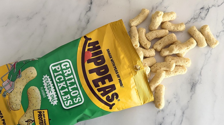 Hippeas spilling out of bag of Grillo's Pickles Hippeas on white marble surface