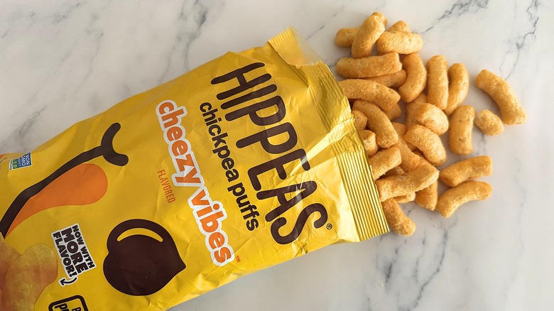 Hippeas spilling out of bag of Cheezy Vibes Hippeas on white marble surface
