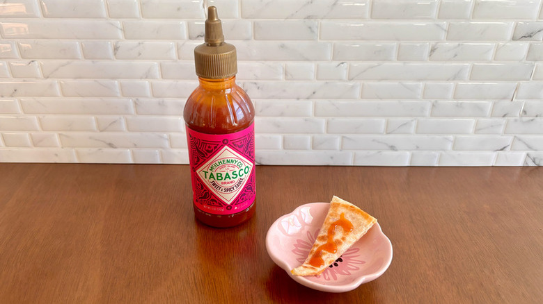bottle of Tabasco Sweet & Spicy Sauce next to a chip with a dab of sauce on it