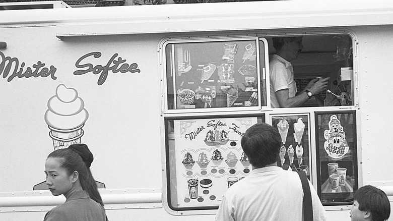 a small group of adults and children gathered around the Mister Softee Ice Cream truck - black and white