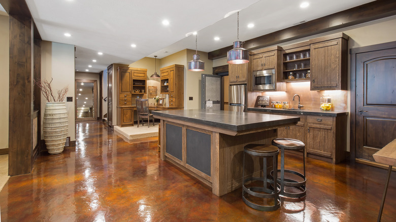 Large kitchen with wood island and cabinetry, featuring warm brown flooring