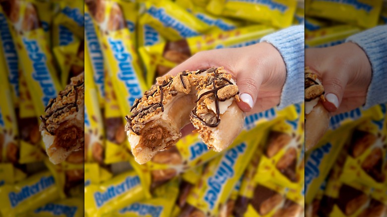 Hand holding Krispy Kreme Butterfinger original filled donut