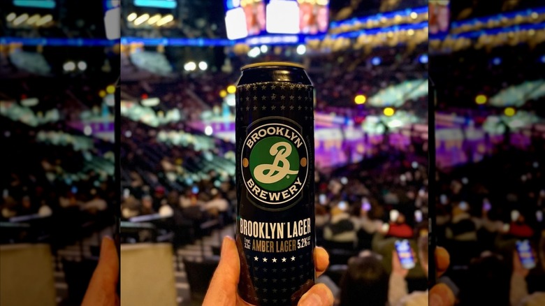 Hand holding Brooklyn Lager at sports game