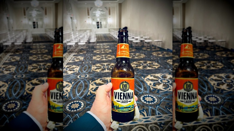 Hand holding Devil's Backbone Vienna Lager with blue carpet background