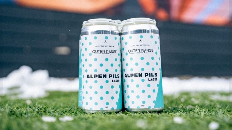 Two cans of Outer Range Alpen Pils Lager sitting on the grass