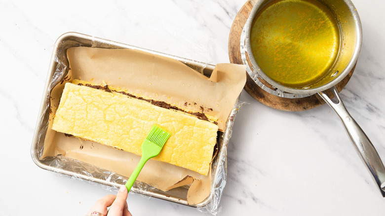 Brushing assembled cake with syrup
