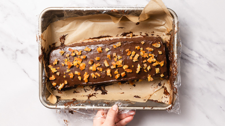 Hand holding pan with garnished cake