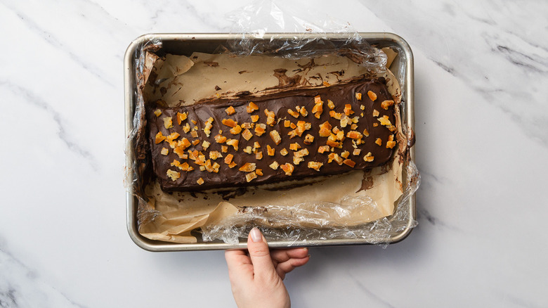 Hand holding pan with garnished cake