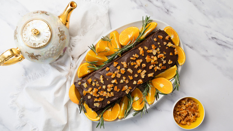 Overhead view of 7-layer chocolate orange Passover cake with teapot and more dried orange peels