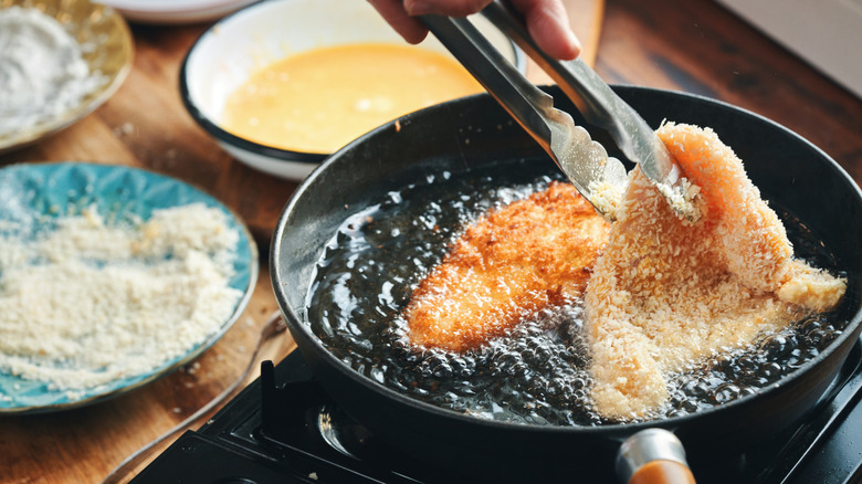 Person frying breaded chicken