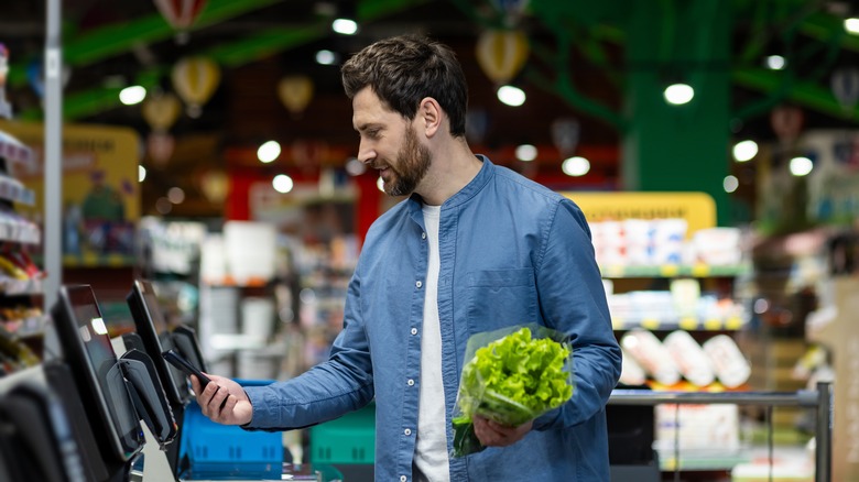 Person buying lettuce at self-checkout in grocery store