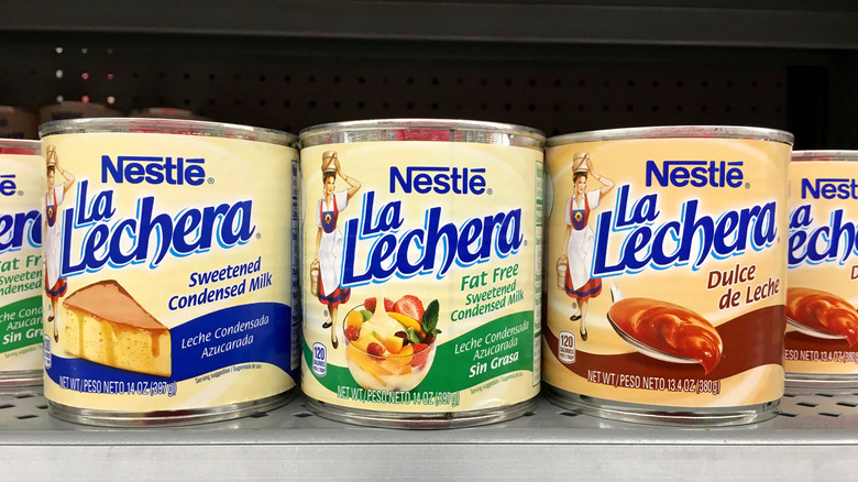 Grocery store shelf with cans of Neslte brand la Lechera.