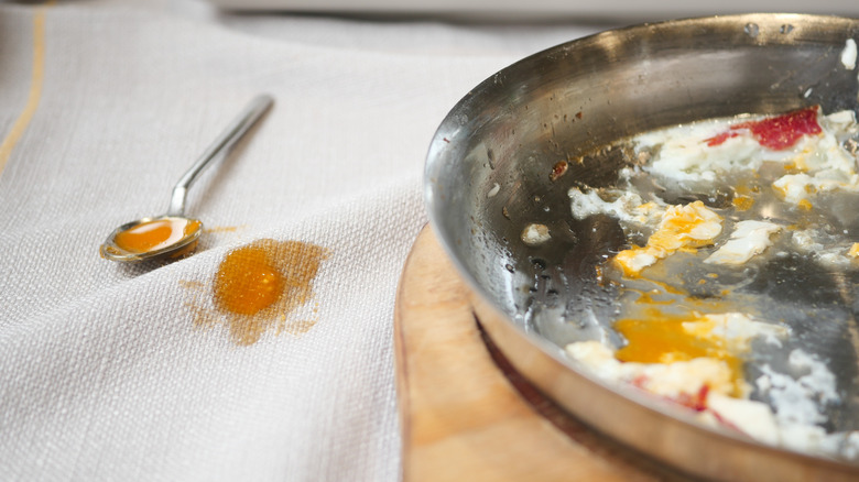 yellow spill on white tablecloth next to dirty metal pan