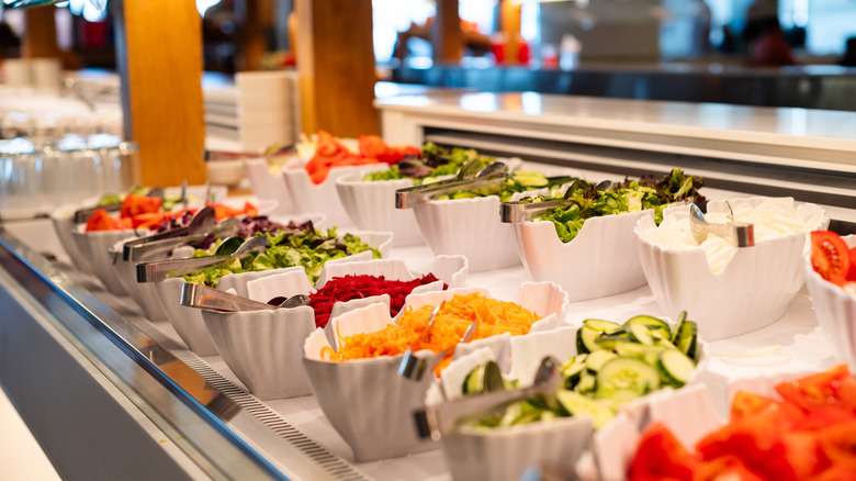 salad ingredients in white bowls on salad bar