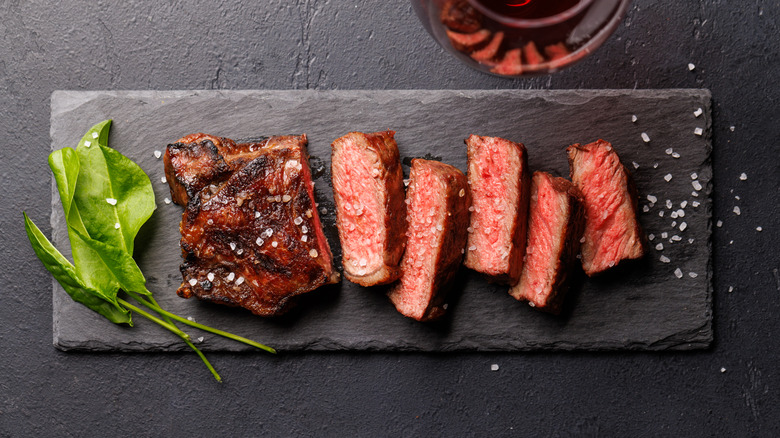 Rare slices of striploin steak on a black background.