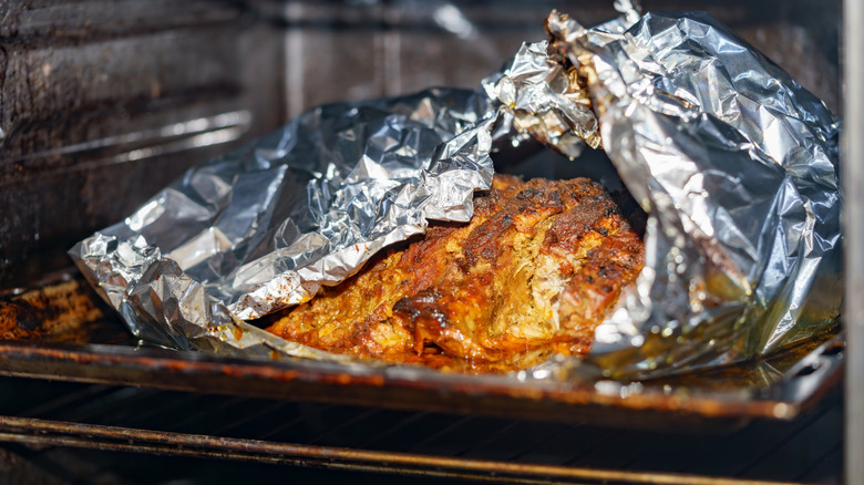 meat cooking in tin foil inside oven