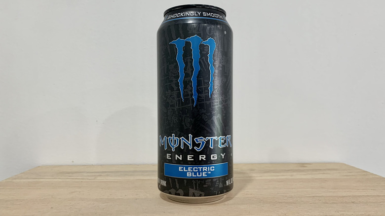 can of Monster Electric Blue on wood table with white background
