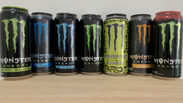 7 cans of Monster on wood table with white background