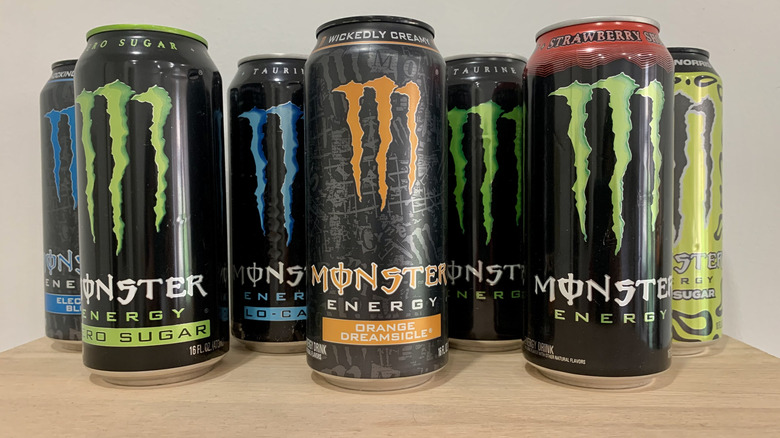 7 cans of Monster on wood table with white background