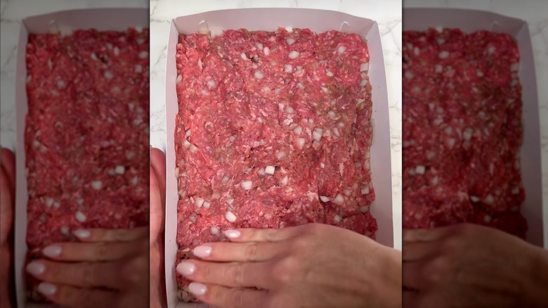 Giant hamburger patty being pressed down