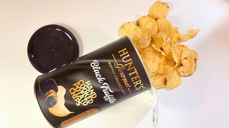 Canister of Hunter's Black Truffle Potato chips on white table with chips spilling out