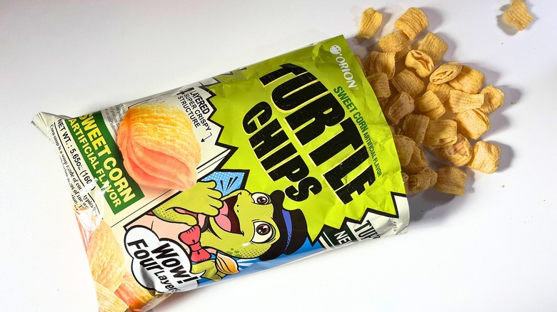 Chips spilling out of bag of Orion Sweet Corn Turtle Chips onto white table