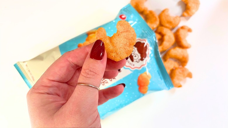 Hand holding Nongshim Salted Butter Roll snack above bag on white table