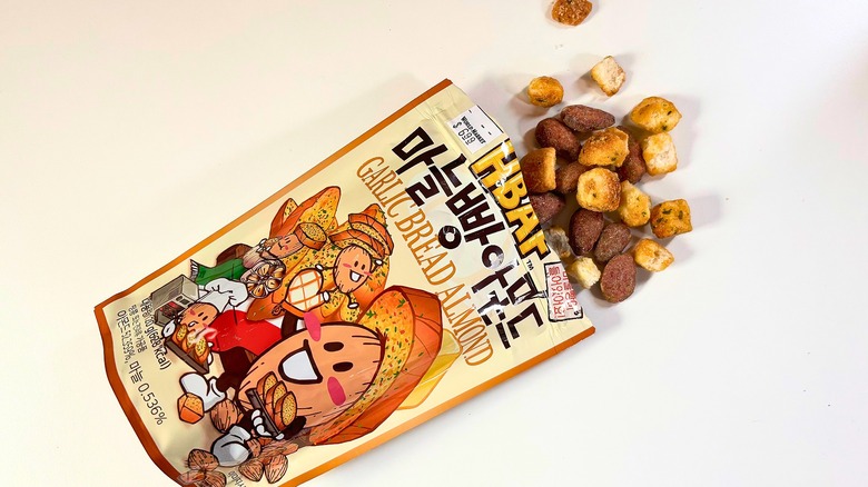 Almonds and croutons spilling out of bag of HBAF Garlic Bread Almonds onto white table