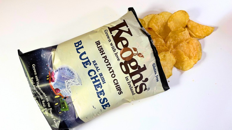 Chips spilling out of bag of Keogh's Blue Cheese Potato Chips onto white table