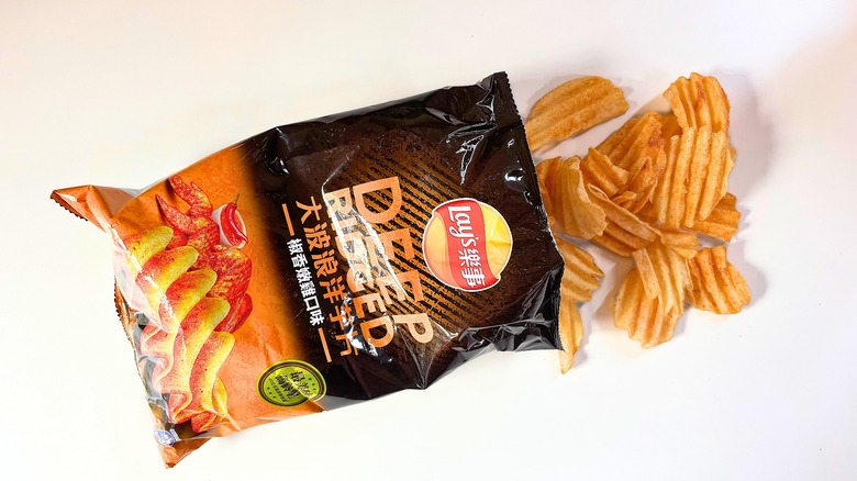 Chips spilling out of bag of Lay's Juicy Chicken Potato Chips onto white table