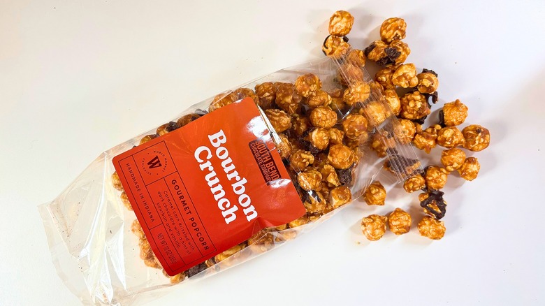 Popcorn spilling out of bag of South Bend Bourbon Crunch Popcorn onto white table