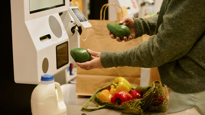 Hand scanning avocados at self checkout station