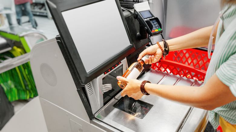 Customer scanning bottle of wine at self-checkout station