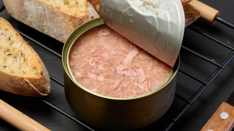 An open tin can of tuna and slices of bread